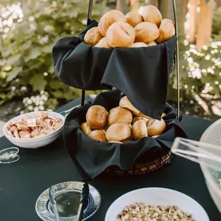 a table with a basket of donuts and bowls of nuts