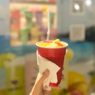 a hand holding a cup of fruit