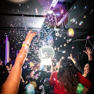 a group of people throwing bubbles at a disco ball