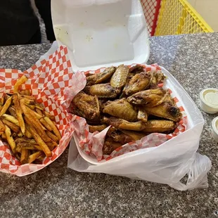 two baskets of chicken wings and french fries