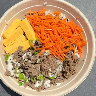 a bowl of food with cheese, carrots, and meat