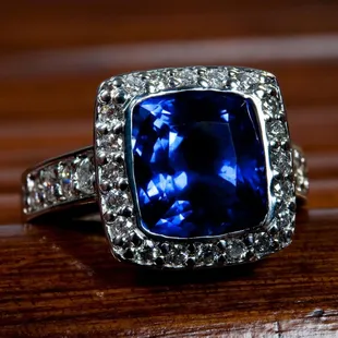 This custom-designed and hand-crafted Cushion Blue Sapphire  is surrounded by bead-set Round Brilliant White Diamonds.