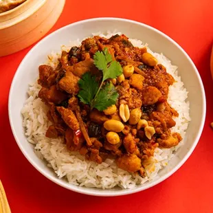 a bowl of chinese food with rice and chopsticks
