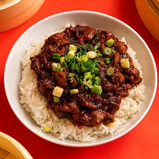 a bowl of chinese food on a red table