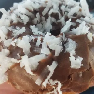 White cake donut, chocolate frosting with a sprinkle of fresh coconut.