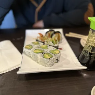 a plate of sushi and a bottle of soy