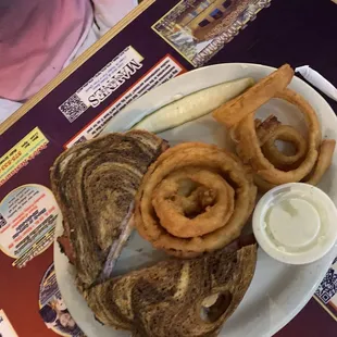 Ruben with onion rings and a pickle