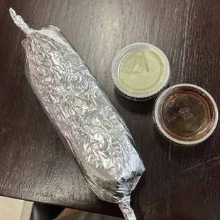 a hot dog wrapped in aluminum foil with condiments