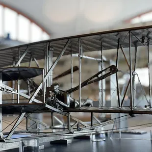 A miniature metal sculpture sits next to a full-sized reproduction of the original 1903 aircraft.