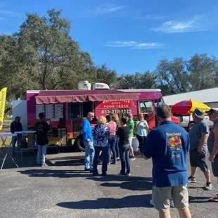 a group of people standing in front of a food truck