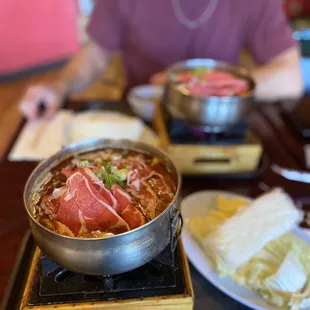 a man sitting at a table with a pot of food