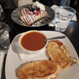Foreground: havarti grilled cheese and tomato bisque Background: berries sweet crepe
