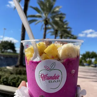 a hand holding a cup of fruit smoothie