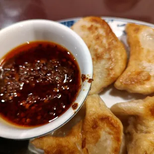 a plate of dumplings and a bowl of sauce
