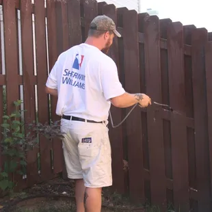 Brandon Wyman treating fence with mold/mildew killer before staining fence.