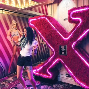a woman standing in front of a neon x sign