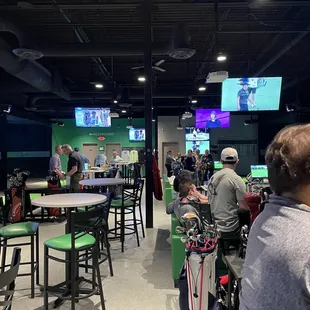 people sitting at tables and watching televisions