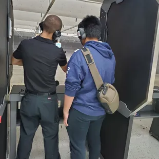 Employee teaching how to handle a gun to a first timer.