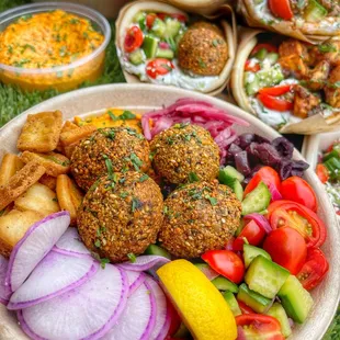 a plate of falafeli, salad, and pitas