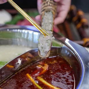 a person holding chopsticks over a dish of food