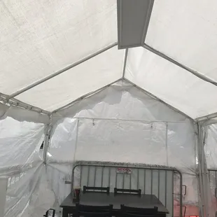 Tent in parking lot has 4 tables.