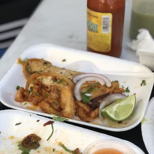 two plates of food and a bottle of sauce