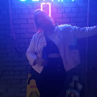 a woman posing in front of a neon sign