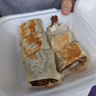 two burritos in a styrofoam container