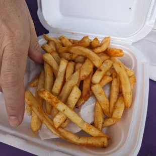 a person holding a container of french fries