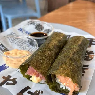 two sushi rolls on a plate with dipping sauce