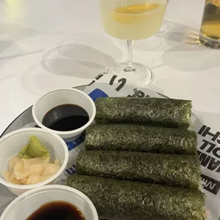 a plate of sushi rolls and dipping sauces