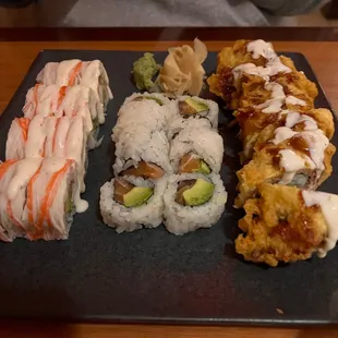 various types of sushi on a black plate
