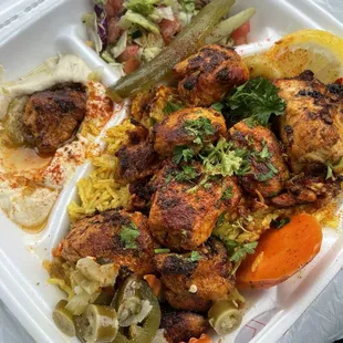 Chicken skewers with rice and hummus. A salad and veggies.