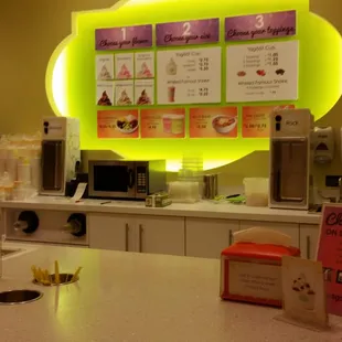 a coffee shop counter with a menu on the wall