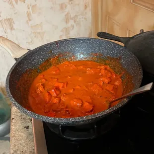 a wok on a stove with a pot of soup in it