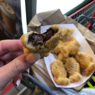 a hand holding a pastry with a bite taken out of it