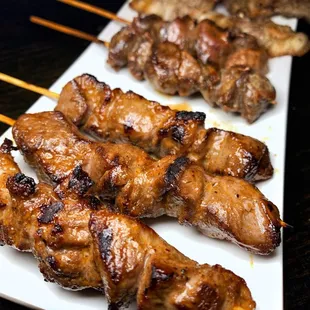 several skewered meats on a white plate