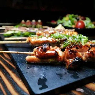 several skewers of food on a black plate