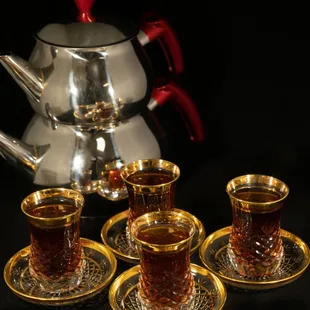 a silver teapot and four cups of tea