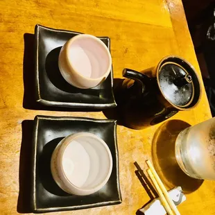 a wooden table with two bowls of food and chopsticks