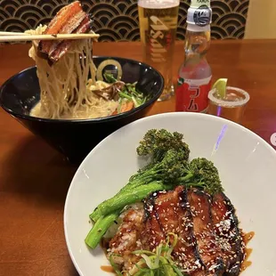 a bowl of ramen noodles and a plate of broccoli