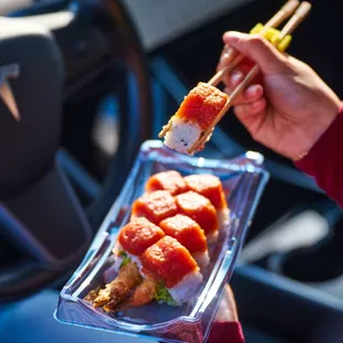 a person holding a tray of sushi