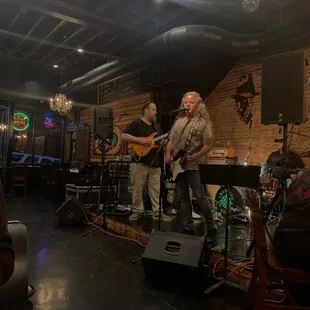 two men playing guitar and singing