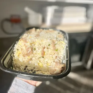 a person holding a tray of rice