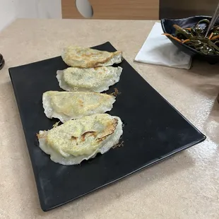 three dumplings on a black plate