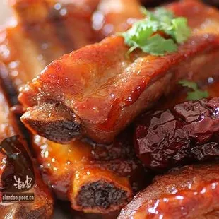 a close up of a plate of ribs with sauce and cherries