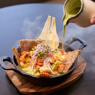 a person pouring sauce over a dish of food