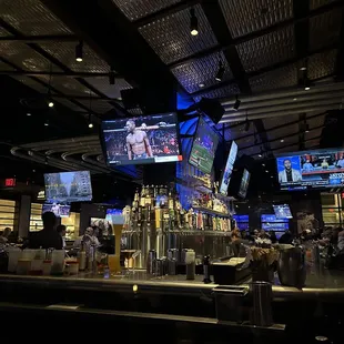 people sitting at the bar watching televisions