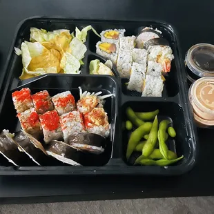 a black tray with a variety of sushi