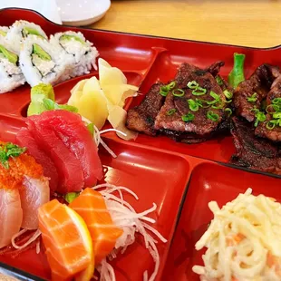 a tray of sushi with meat and vegetables